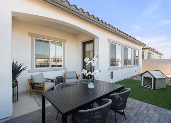 A patio with a table and chairs is set up outside a house.