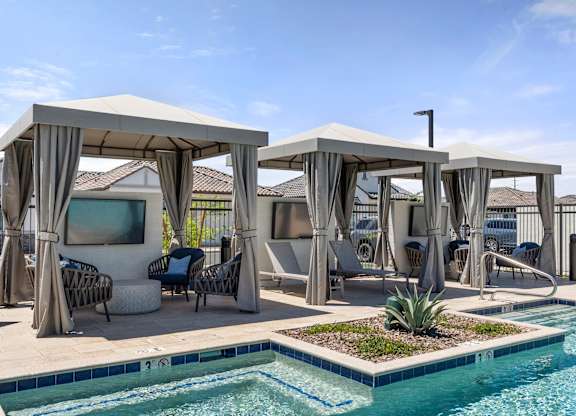 A pool area with a white canopy and a small pond.
