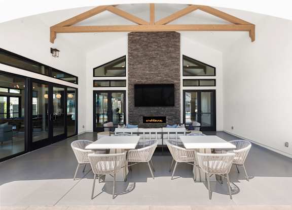 A modern dining room with a stone fireplace and white furniture.