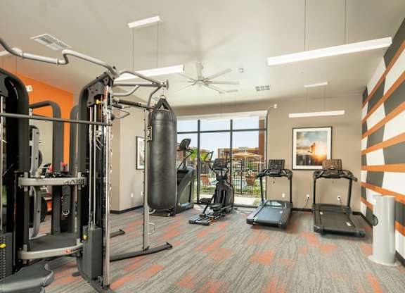 A gym with orange walls and a variety of equipment.