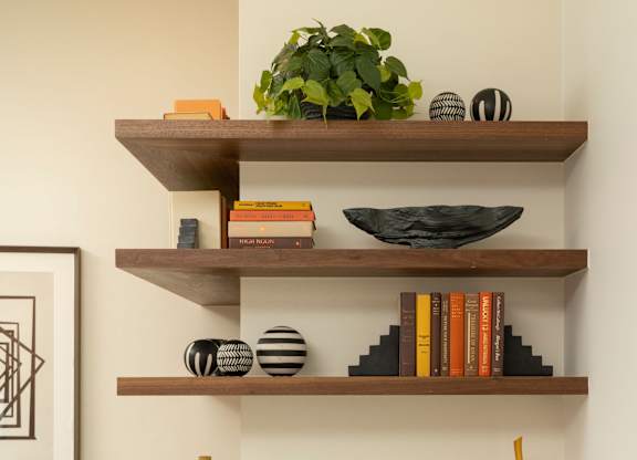 A kitchen with a white counter top and a wooden shelf above it.