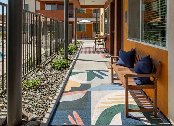 A long hallway with a bench and a colorful floor mat.