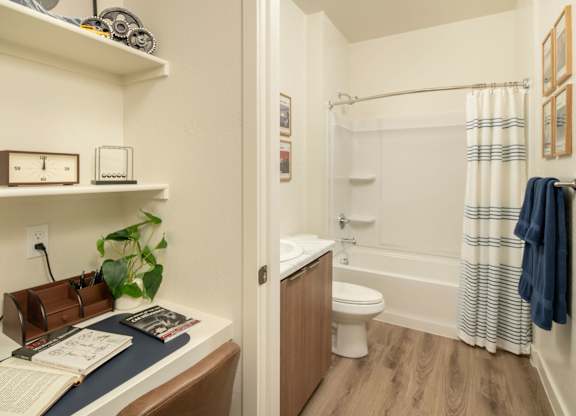 A bathroom with a toilet, sink, and a chair.
