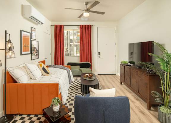 A living room with a bed, a chair, and a television.