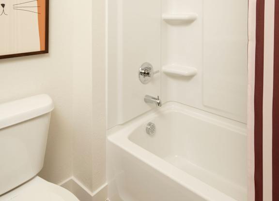 A white toilet sits next to a white bathtub in a bathroom.