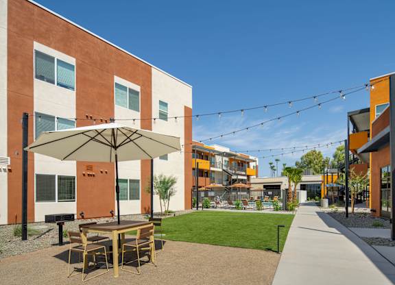 A patio with a table and chairs is surrounded by buildings.