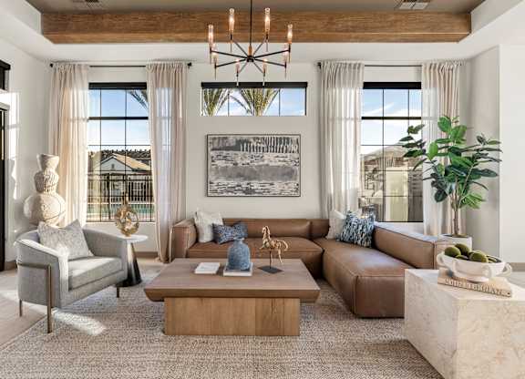 A living room with a large couch, a coffee table, and a chandelier.