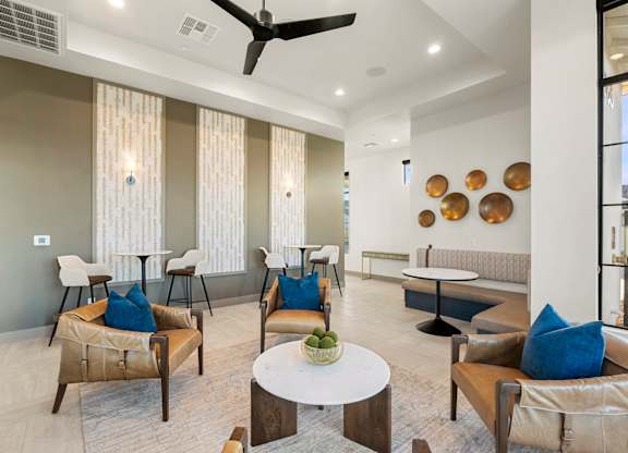 A living room with a fan, chairs, and a table.