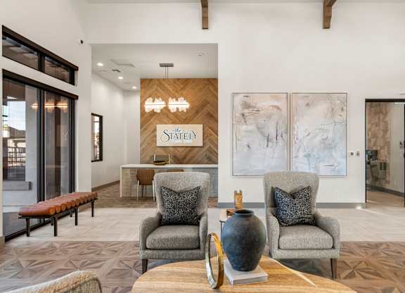 Two grey chairs with pillows sit in front of a wooden sign that says "STATELY".