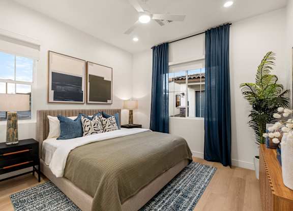 A bedroom with a large bed and a window with blue curtains.