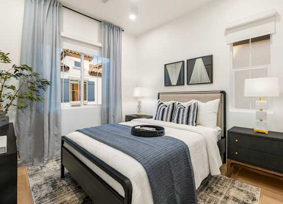 A bedroom with a large bed and a nightstand with a lamp.