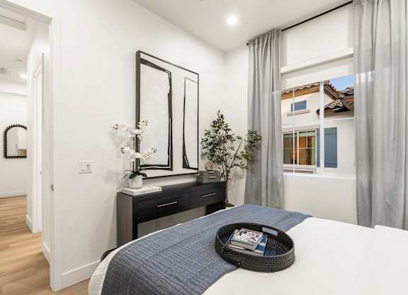 A bedroom with a bed, nightstand, and a window with curtains.