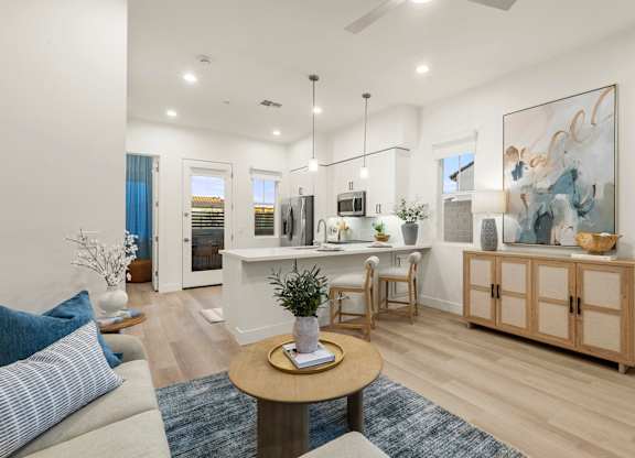 A living room with a white sofa, a wooden coffee table, and a painting on the wall.