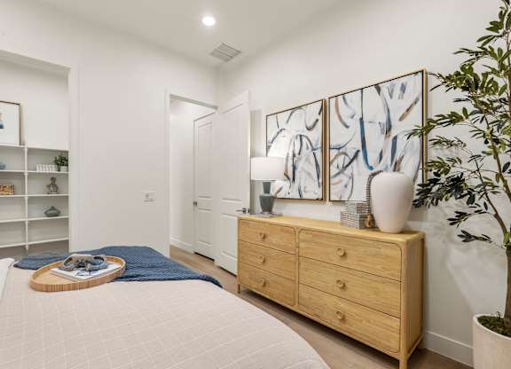 A bedroom with a bed, dresser, and a painting on the wall.