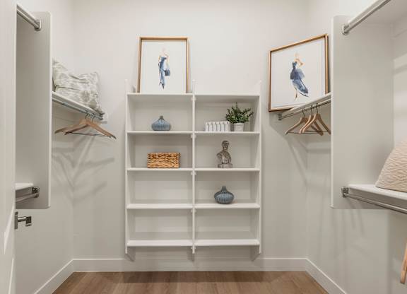 A white shelving unit with decorative items and two framed pictures on the wall.