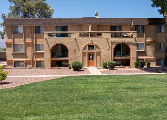 A large tan building with a brown roof and a green lawn in front.