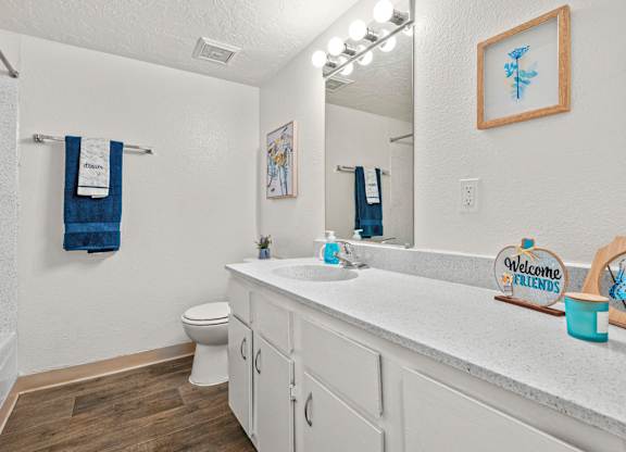 A bathroom with a toilet, sink, and a mirror.