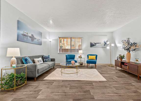 A living room with a grey couch, blue chairs, and a rug.