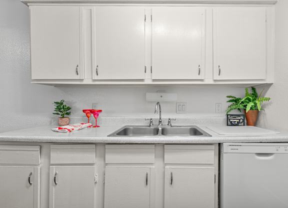 A white kitchen with a sink and cabinets.