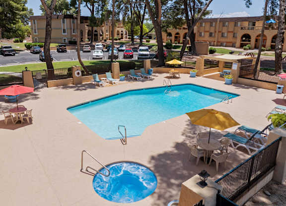 A large swimming pool with a hot tub in the middle of a patio area.