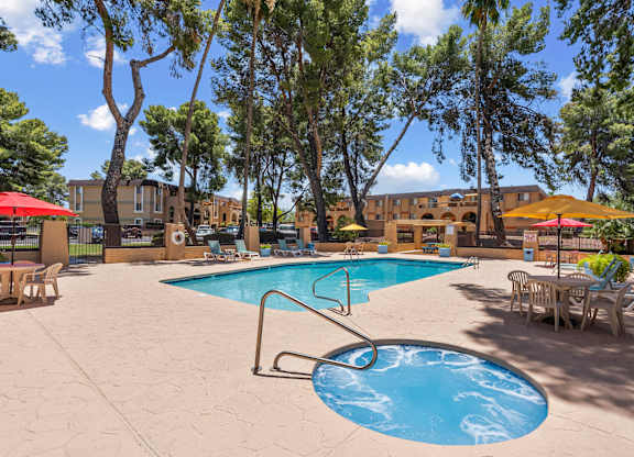 A pool surrounded by trees and chairs.
