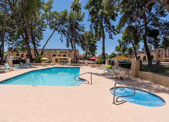 A pool surrounded by trees and chairs.