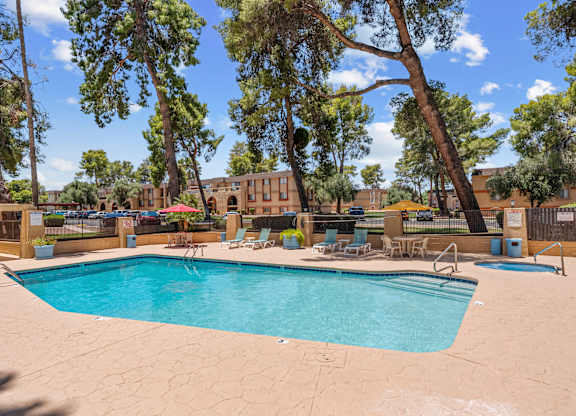 A large swimming pool surrounded by trees and chairs.