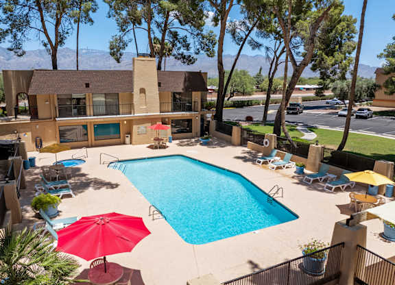 A red umbrella is on the patio of a house with a pool.