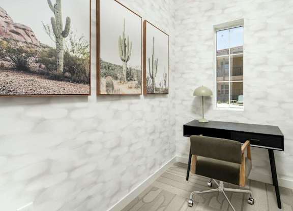 A room with a black desk and a cactus print on the wall.