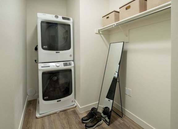 A white microwave oven is on the floor next to a mirror.