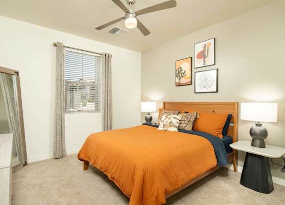A bedroom with a bed, a ceiling fan, and a window with curtains.