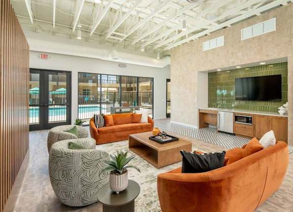 A modern living room with a flat screen TV and a glass door leading to a balcony.