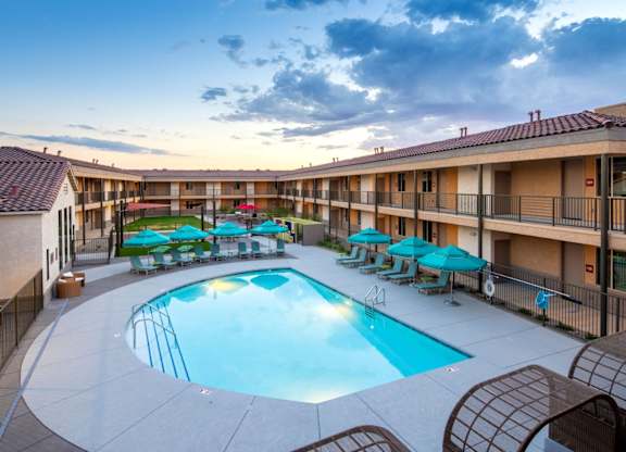 A large outdoor swimming pool surrounded by lounge chairs and umbrellas.