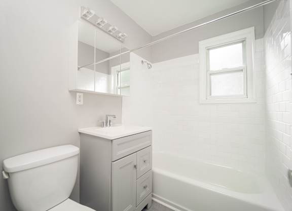 a white bathroom with a toilet and a tub at Encore 99, East Haven
