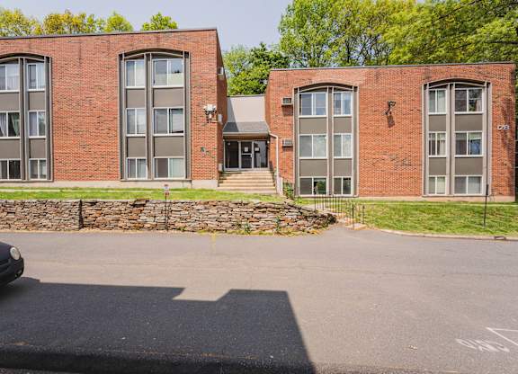 the front of a red brick building with a parking lot at Springwood Gardens, New Britain