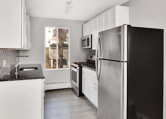 a kitchen with a black refrigerator and white cabinets at Springwood Gardens, Connecticut