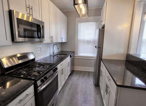 a kitchen with white cabinets and black counter tops at The Packard, West Hartford