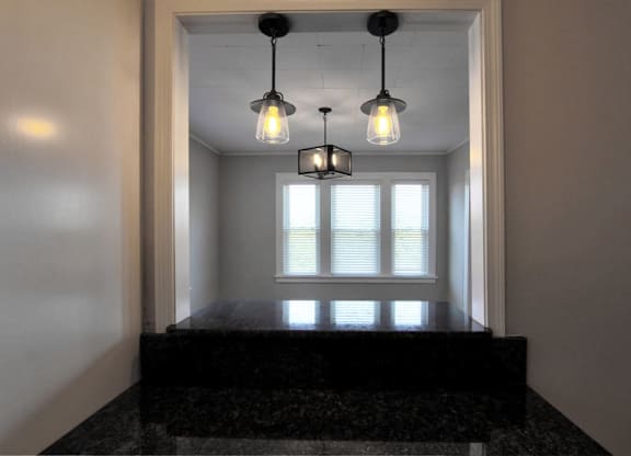 three lights hanging over a window in a room with a black counter at The Packard, West Hartford, 06119