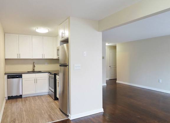 an empty kitchen with white cabinets and a stainless steel refrigerator at The Packard, West Hartford