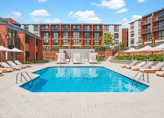 a pool with chairs and umbrellas in front of an apartment building at Up House, Connecticut
