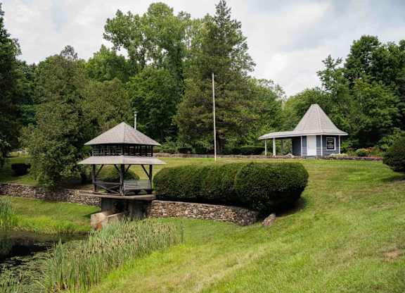 a gazebo and a pavilion in a park next to a river at Woodbury Knoll, Woodbury, 06798