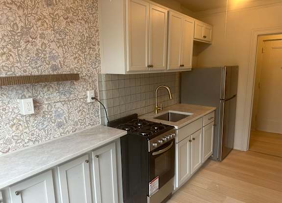 A kitchen with a black stove top oven and a refrigerator.