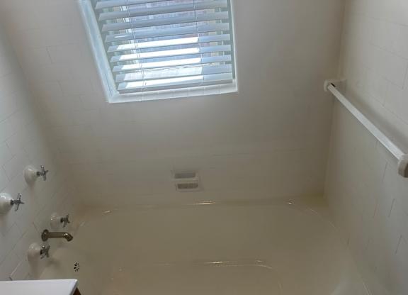 A white bathroom with a skylight and a bathtub.
