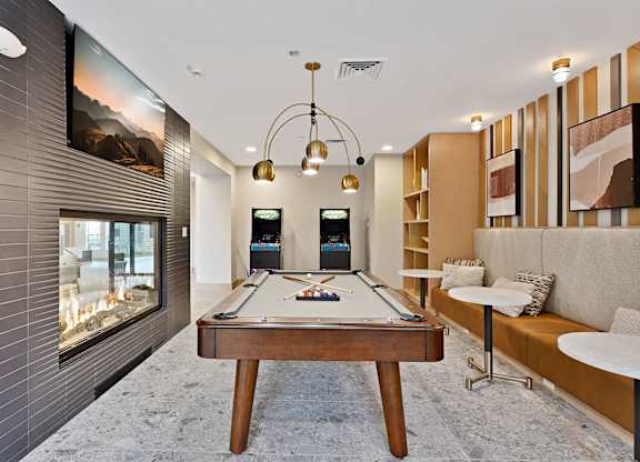 A pool table is in the middle of a room with a television and a couch.
