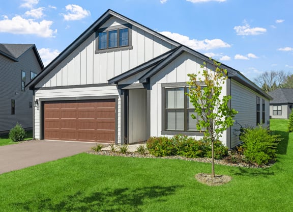 a home with a brown garage door in front of a green lawn