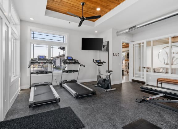 a home gym with treadmills and a tv on the wall