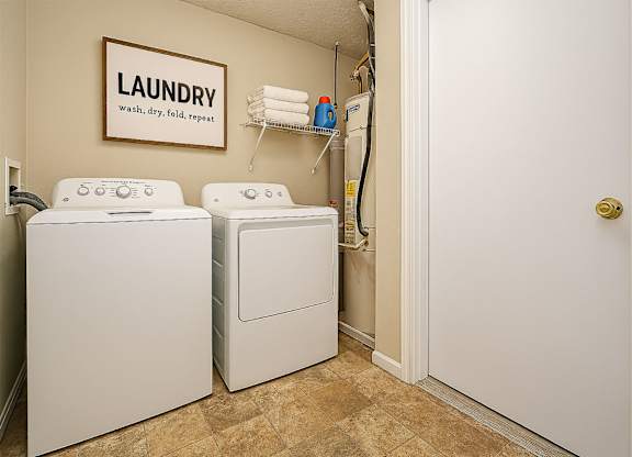 A laundry sign hangs on a wall above a washer and dryer.