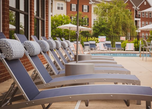 a row of chaise lounges in front of a pool with umbrellas