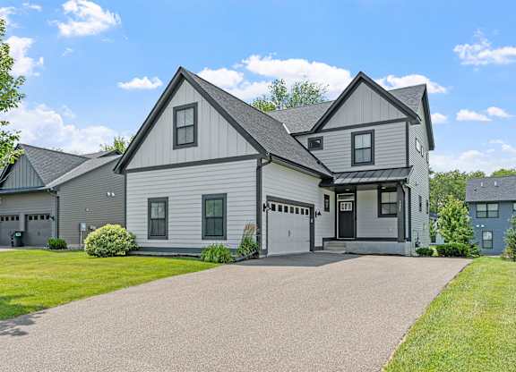 A large house with a grey roof and a driveway in front.