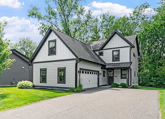 A white house with a black roof and a garage door.